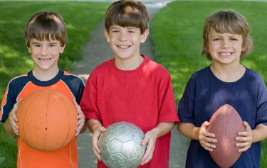 Boys holding basketball, football and soccer ball