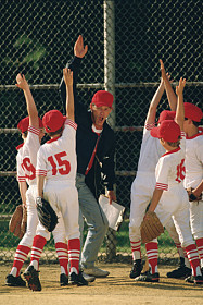 Youth baseball coach exchanges high fives with team