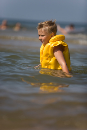 Boy in yellow life jacket in ocean surf