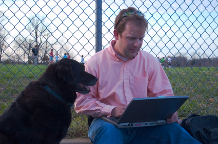 Father multi-tasking with dog at sports practice