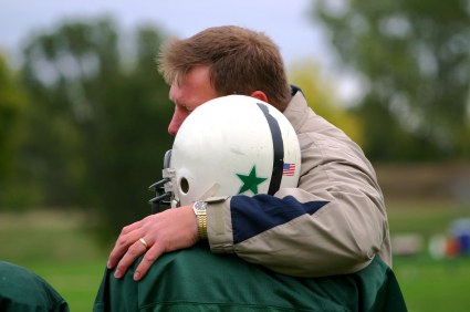 Football coach with arm around young player