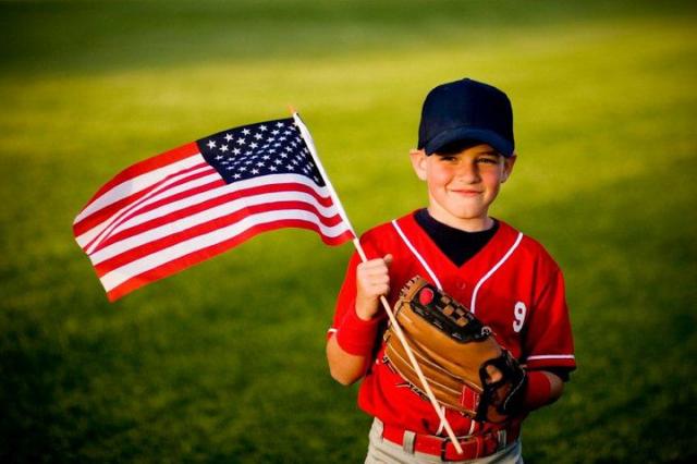 Youth baseball player waving American flag