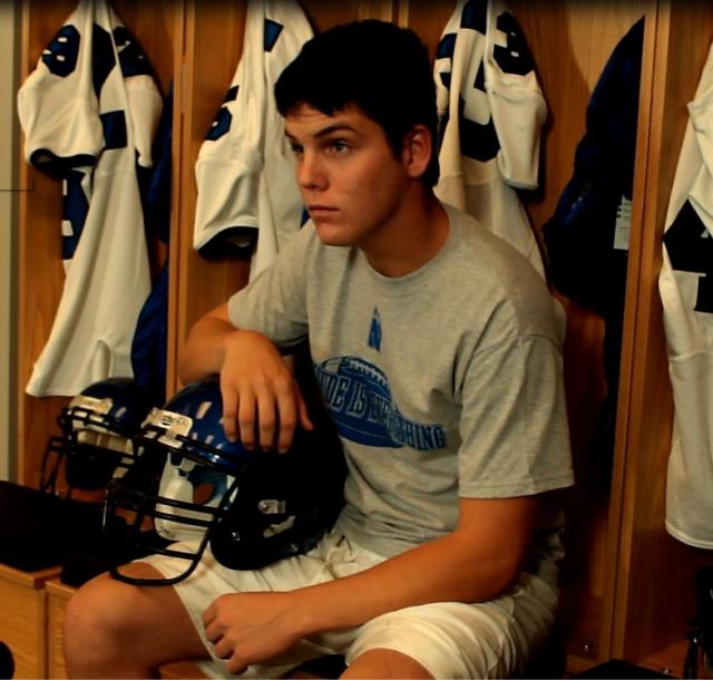 Football player at locker with helmet