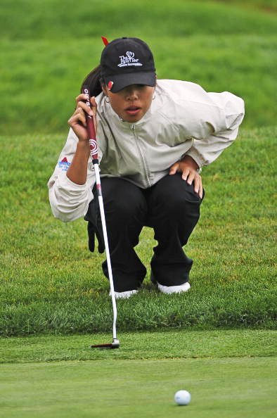 Young African-American golfer lining up put