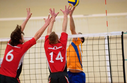 Volleyball players going for ball at net