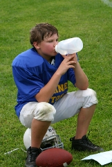 Young football player drinking from water jug