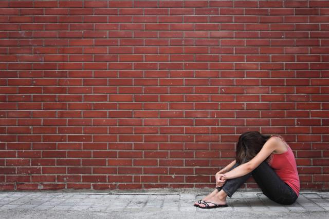 Sad teenage girl in front of brick wall