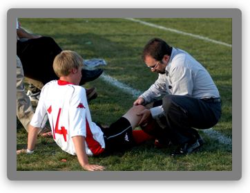 Lawrenceville School athletic trainer Mike Goldenberg examines a soccer player's knee