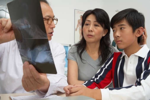 Orthopedic surgeon discussing x-ray with Asian-American mom and her son