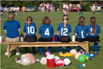 Coach with young girls soccer players on bench