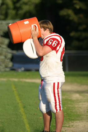 Football player gulping fluids after practice